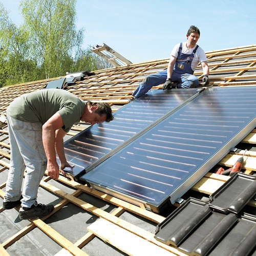 Montaż kolektorów słonecznych na dachu.
