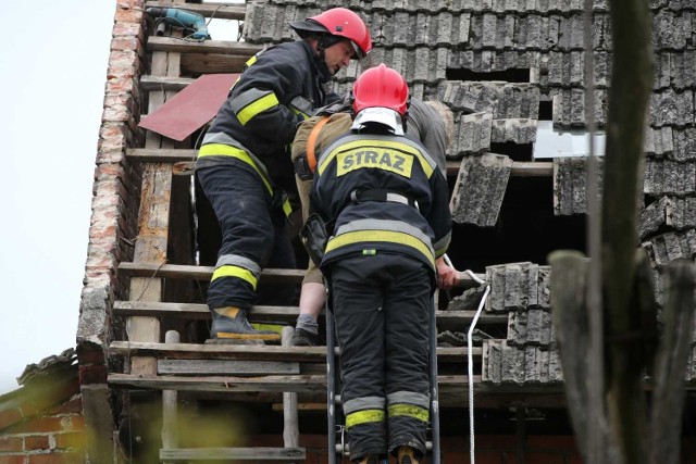 Strażacy wynoszą z dachu rannego mężczyznę.