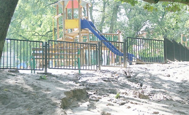 Rwący strumień wody wypłukał piasek z placu zabaw w parku