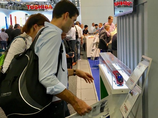 Ponad 100 spotkań na stoisku, w tym z kluczowymi klientami, jak choćby DB, konferencja prasowa z udziałem PFR, jako nowego właściciela i umowa z PKP Cargo - tak w skrócie można podsumować obecność bydgoskiej na tegorocznych targach InnoTrans, które odbywały się w zeszłym tygodniu w Berlinie. Pesa wychodzi z kryzysu Dla Pesy berlińskie targi były bardzo ważne przede wszystkim ze względu na zainteresowanie klientów, dostawców i biznesowych partnerów ze świata sytuacją wychodzącej z kryzysu firmy. Stąd też specjalny briefing dla zagranicznych i polskich mediów z udziałem prezesa Pesy i wiceprezesa Polskiego Funduszu Rozwoju. Podczas spotkania z mediami poinformowano o finalizacji procesu przejmowania przez PFR udziałów w spółce oraz osiągniętym porozumieniu z bankami w sprawie dalszego finansowania działalności PESA.  - Kończymy negocjacje z bankami i ubezpieczycielami. Będziemy gotowi do podpisania umowy na przełomie września i października. W konsorcjum zaangażowane są instytucje komercyjne oraz te z udziałem Skarbu Państwa -  zapowiedział Marcin Piasecki, wiceprezes PFR.Stan realizacji największego kontraktu z DBPrezes Pesy przedstawił również stan realizacji kluczowego dla spółki kontraktu na dostawę pojazdów dla Deutsche Bahn. W tej chwili w Niemczech jest już 16 dwuczłonowych LINKów, do końca października będzie ich 20, a DB Regio rozpoczęło już ich eksploatację - wyprodukowane w Bydgoszczy pojazdy wożą już pasażerów w okolicach Dortmundu. - Z naszego punktu widzenia bardzo ważne jest to, że po wprowadzeniu pojazdów do ruchu i dobrych opiniach, które zbierają, DB zgodziło się na zmianę sposobu rozliczenia kontraktu - pierwsze płatności już wpłynęły do PESA. Co równie ważne - rozmawiamy z władzami DB nie tylko o tym projekcie, ale o możliwościach współpracy w przyszłości - poinformował Krzysztof Sędzikowski.Na stoisku Pesy gościł prezes  DB AG Richard Lutz, z którym spotkali się Krzysztof Sędzikowski i Marcin Piasecki. Właśnie podczas tej rozmowy omówiono nie tylko stan realizacji obowiązującej umowy, ale także możliwości współpracy w przyszłości.  - Prezes DB zapewnił, że jest zainteresowane dalszą współpracą z PESA i kolejnymi zamówieniami, nie tylko na pojazdy spalinowe. Mam nadzieję, że do roboczego spotkania w tej sprawie dojdzie jeszcze przed końcem tego roku  - potwierdził Sędzikowski.Deklaracje współpracy w przyszłości padały także podczas rozmów z innymi przewoźnikami, a wszystko wskazuje na to, że w najbliższych latach eksport PESA wzrośnie znacząco i to zarówno na rynkach zachodniej, jak i wschodniej Europy.Odbywające się co dwa lata w Berlinie targi InnoTrans to najważniejsze światowe spotkanie branży kolejowej, w tym roku uczestniczyło w nich 3062 wystawców, a producenci pokazali 155 pojazdów szynowych.Mimo, że PESA nie prezentowała swoich produktów na Innotrans, to okładkę pierwszego numeru targowego Messe Kurier zdobiło, ku zaskoczeniu części mediów, zdjęcie Pesa Dart z poprzednich targów.Lokomotywa z bydgoskiej Pesy bez maszynisty - ruszają prace projektoweW najbliższym czasie bydgoską firmę czekają dwie ważne uroczystości - najpierw 27 września w Rzeszowie zakończenie kontraktu na dostawę ELF2 dla Województwa Podkarpackiego i prezentacja ELF2 w specjalnej malaturze nawiązującej do 100 - lecia odzyskania przez Polskę niepodległości, a 8 listopada w Dortmundzie uroczysta prezentacja spalinowych LINK dla Deutsche Bahn.