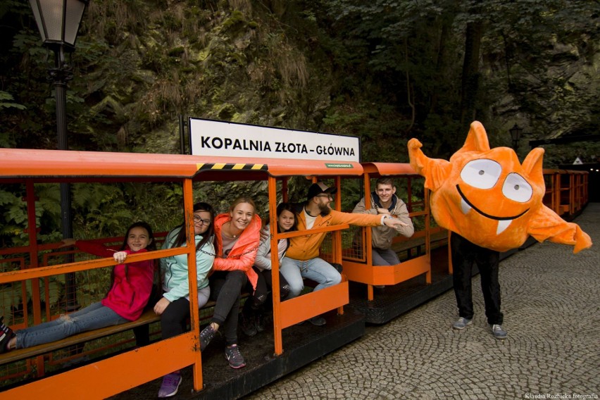 Pomarańczowa kolejka wozi turystów po kompleksie Kopalni...