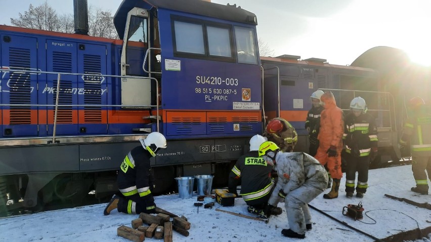 Strażacy wypompowują paliwo z uszkodzonej lokomotywy.