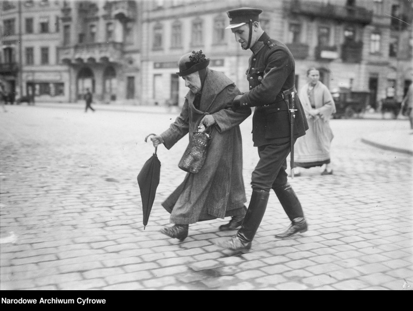 Policjant przeprowadzający staruszkę przez ulicę...