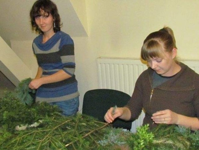 Monika Puk oraz Kamila Zaniewska przygotowują z zielonych gałązek podstawy pod swoje stroiki