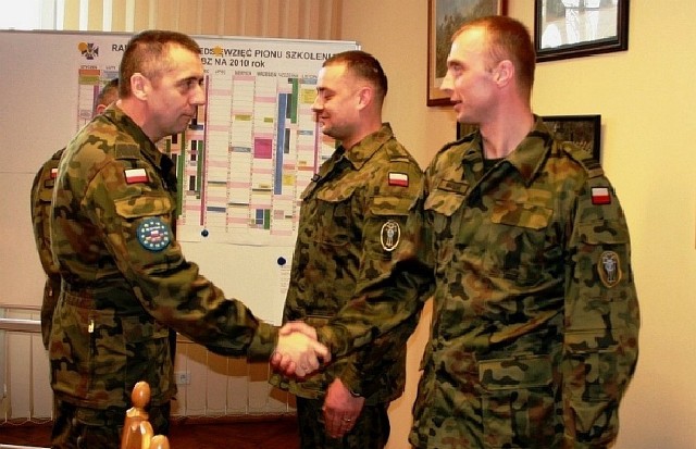 Gen. bryg. Sławomir Wojciechowski (z lewej) gratuluje st. kpr. Rafałowi Walickiemu. Na drugim planie st. szer. Marek Sztuba.