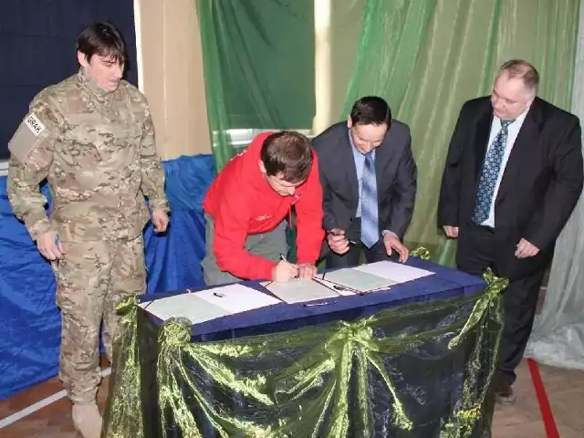 Major Jacek Kowalik (w mundurze) oraz (od prawej) Gustaw Saramański, wicestarosta opatowski i Tomasz Świątek, dyrektor Zespołu Szkół numer 1 w Opatowie, podpisują akt objęcia patronatem klasy mundurowe.