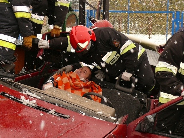 Strażacy wydobywają z auta ofiary wypadku na przejeździe kolejowym.