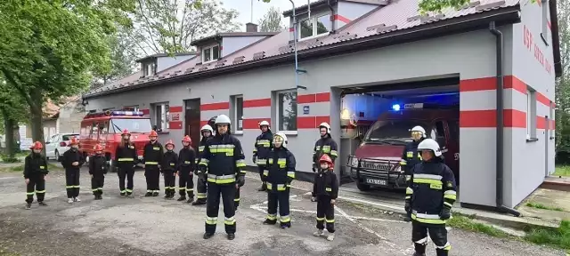 Młodzieżowa Drużyna Pożarnicza OSP Gorzeń Dolny na tle sędziwych samochodów.