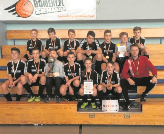 Młodzicy Pogoni ze swoimi trofeami i trenerem.