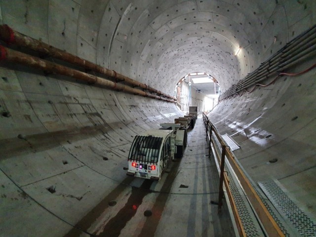 Tunel w Świnoujściu nabiera realnych kształtów. Gdy zostanie oddany do użytku, kolejki pojazdów czekających na prom odejdą w zapomnienie. Olbrzymia maszyna TBM do budowy tunelu pod Świną etap rozruchu ma już za sobą. Osiągnęła już zakładane tempo drążenia, które wynosi ok. 10 metrów na dobę. Do tej pory zostało wydrążonych ponad 130 metrów, a to oznacza, że cała maszyna jest już w tunelu. Tunel będzie miał długość 1,44 km, a jego drążenie zakończy się jesienią. Jednak przewiercenie się z wyspy Uznam na wyspę Wolin nie będzie oznaczało końca prac. Tunel będzie miał przekrój kolisty, tak jak tarcza maszyny TBM. Aby mogły się nim poruszać pojazdy, trzeba będzie wykonać płytę, na której będzie zlokalizowana jezdnia. Pod jezdnią zostanie umieszczona galeria ewakuacyjna wraz z większością instalacji tunelu. Ważnym elementem będą również wyjścia awaryjne do galerii ewakuacyjnej. Wykonywane zostaną również systemy wentylacji, przeciwpożarowe, zarządzania ruchem i monitoringu. Tunel będzie jednorurowy i powstanie w nim dwupasowa jezdnia. Dzięki tej inwestycji Świnoujście zostanie w sposób stały skomunikowane z resztą Polski. Obecnie komunikację zapewniają przeprawy promowe, które mają mocno ograniczoną przepustowość i są zależne od warunków pogodowych.   Zakończenie inwestycji przewidziane jest na wrzesień przyszłego roku.  Wideo: "Potężne wiertło skruszy nie tylko warstwy ziemi, ale i bariery niemożności". Pod okiem premiera i prezesa Kaczyńskiego rozpoczęto drążenie tunelu w Świnoujściuźródło: TVN24/x-newsCzytaj także: Tak powstaje tunel w Świnoujściu. Zdjęcia z miejsca budowy robią wrażenie