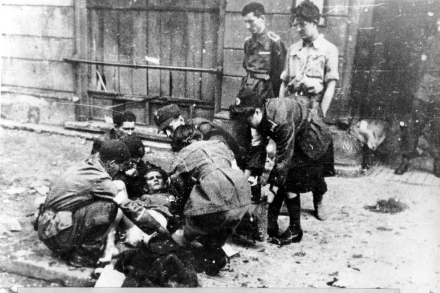 Podczas powstania warszawskiego kobiety angażowały się głównie w pracę łączniczek i sanitariuszek. Na zdjęciu: udzielanie pomocy rannemu na ulicy. Sierpień 1944.