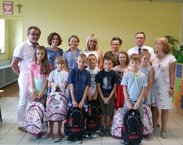 Dzieci obdarowane plecakami i ofiarodawcy