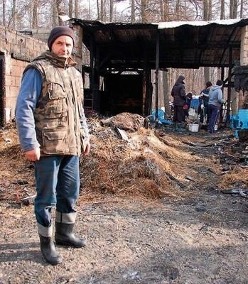 Bogusław Kłusek przed spalonymi zabudowaniami stajni i stodoły FOT. PAWEŁ CHWAŁ