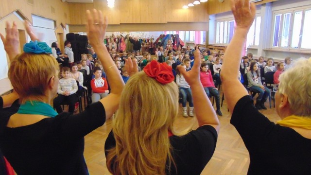 W spotkaniach z dziećmi biorą udział Poznańskie Senioritki. Ewa Wodzyńska wprowadza uczniów w magiczny świat muzyki chóralnej, tłumaczy pojęcia związane z chórem i muzyką chóralną. co więcej dzieci aktywnie uczestniczą w zajęciach, śpiewając, wyklaskując rytmy