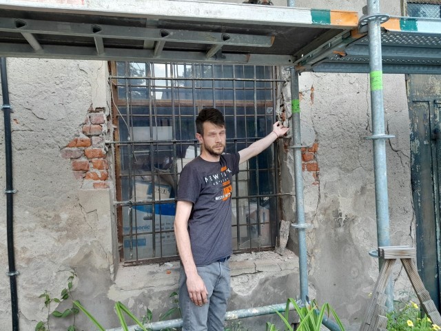 Krzysztof Jóźwiak, właściciel mieszkania na pierwszym piętrze, pokazuje powiększające się pęknięcia na fasadzie budynku.