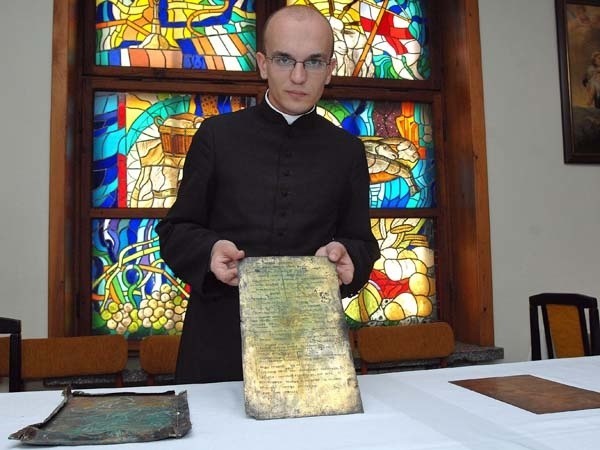 Ksiądz Karol Kubicki z Parafii Katedralnej w Koszalinie pokazuje skarby, jakie ukryte były przez kilka w kuli pod krzyżem na wieży katedry.