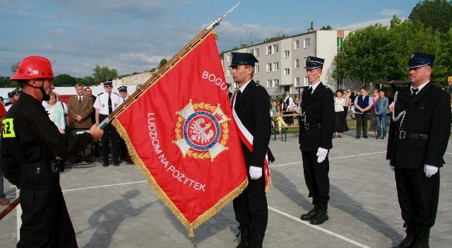 Naczelnik OSP Krzysztof Hacaś (z lewej) przekazuje sztandar Lechowi Kobusowi, Adamowi Piórko i Adamowi Trojankowi.