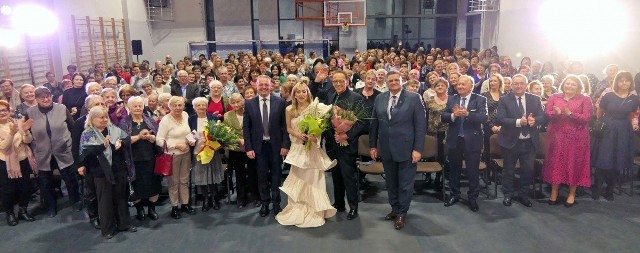 "Rodzinna" fotografia uczestników spotkania z okazji Dnia Kobiet 2023,  jakie odbyło się w sali Szkoły Podstawowej w Tupadłach (gm. Inowrocław). W środku popularni artyści: Ewa Kuklińska i Jacek Borkowski