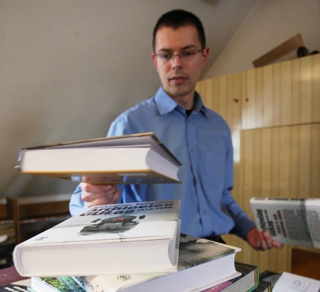 Stanisław Kałuc pokazuje książki, które udało się kupić za pieniądze odzyskane od dłużników biblioteki.