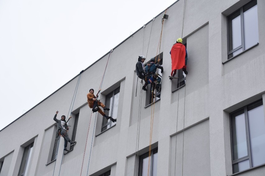 Alpiniści przemysłowi w strojach superbohaterów myją okna w...