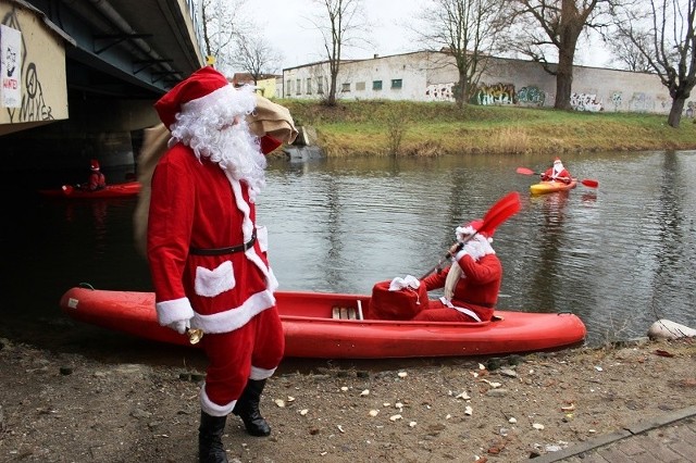 Święty Mikołaj zacumował swój kajak przy moście i zszedł na ląd, by rozdawać dzieciom słodkości.
