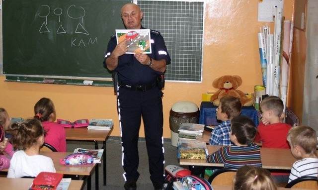 Dzielnicowy Jacek Łapot objaśnia dzieciom zasady ruchu drogowego.