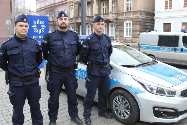 Policjanci - mł. asp. Łukasz Duczkowski, sierż. szt. Przemysław Kachel i sierż. Artur Górski na tle radiowozu