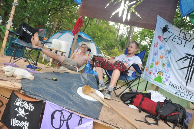 Jedni budują je z drewna, inni wykorzystują do tego folię i taśmę klejącą, jeszcze inni przywożą z domu... meble! Wioski na Przystanku Woodstock 2017 naprawdę robią wrażenie.- Zbudowaliśmy scenę i będziemy tu grali koncerty. Mamy agregat, głośniki - wyliczają chłopaki z Opola. Rozbili się przy podejściu pod woodsotckową górkę w pobliżu stoisk gastronomicznych. Przywieźli ze sobą całą masę drewna i to z niego zbudowali scenę. Takich miejsc na woodstockowym polu jest więcej. Każdy chce jak najbardziej wyróżnić swój namiot i obóz. Są więc dekoracje, transparenty, głośna muzyka (z odtwarzacza, ale często również na żywo). Zobaczcie woodstockowe wioski na naszych zdjęciach.Chcesz wiedzieć kto zagra na Przystanku Woodstock 2017? Przystanek Woodstock 2016: zespoły, koncerty kto zagraWszystkie informacje o Przystanku Woodstock 2017 w Kostrzynie nad Odrą:  Przystanek Woodstock 2017: koncerty, zdjęcia, filmy, informacje