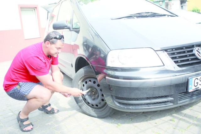 Tomasz Rybak przy samochodzie ze zniszczonymi felgami.