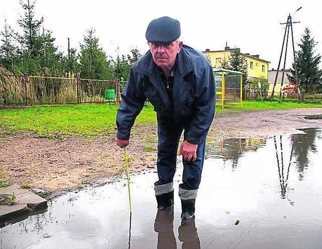 Zdzisław Polek w kałuży stojącej wzdłuż „nowej” drogi. - Sami byśmy to lepiej naprawili, ale to droga powiatu - kręci głową