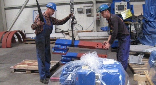 Pracownicy Technicala przenoszą silniki elektryczne na specjalnej suwnicy 