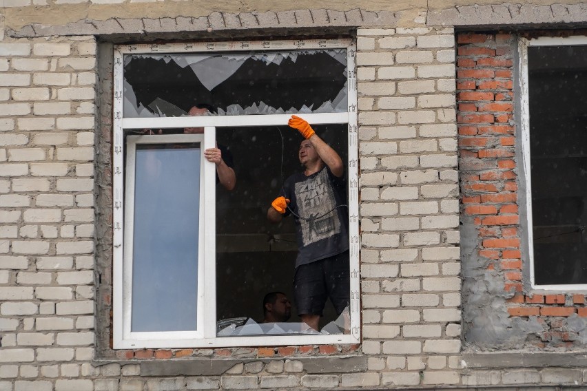 Mężczyzna usuwa rozbite szkło w oknie na terenie jednego z...