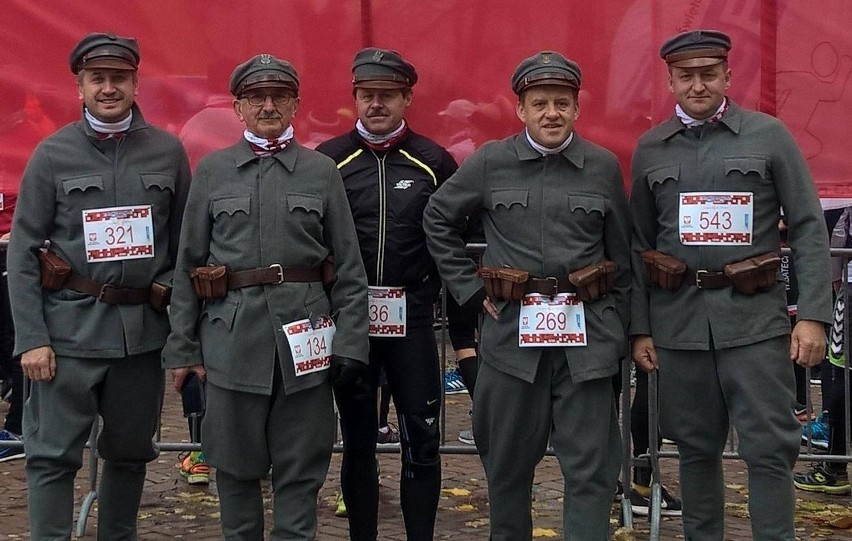 Ubrani w mundury legionistów z wielką flagą Polski biegli...