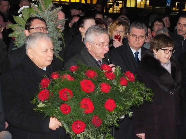 Jarosław Kaczyński z kwiatami przed tablicą poświęcona jego mamie Jadwidze Kaczyńskiej