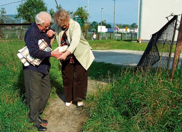 Krok po kroku Jan Olszyński wyprowadza swoją żonę przez dziurę w ogrodzeniu ścieżką wydeptaną przez ludzi, którzy w podobny jak oni sposób chcieli uniknąć 3 zł opłaty za samochód