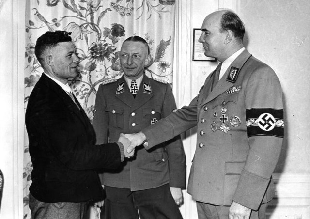 Marzec 1944 - Heinz Reinefarth (w środku) wraz z Arthurem Greiserem wita milionowego Niemca przesiedlonego do Kraju Warty w ramach akcji „Heim ins Reich”