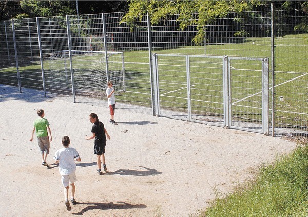 Jak wytłumaczyć dzieciom, że dorośli się kłócą i dlatego oni nie mogą grać w piłkę? Boisko oglądają tylko przez dziury w siatce ogrodzeniowej.