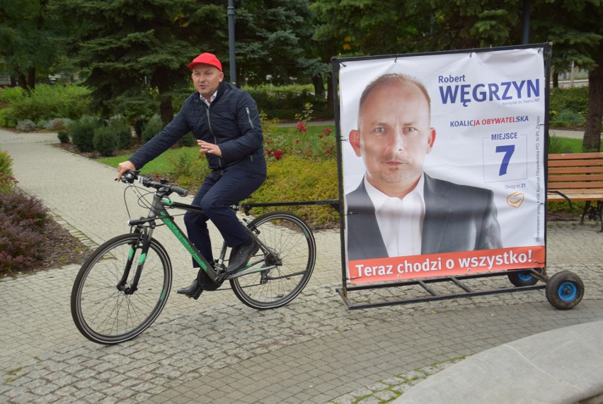 Robert Węgrzyn ciągnie na rowerze przyczepkę ze swoim banerem wyborczym. Chce tak zjeździć całą Opolszczyznę