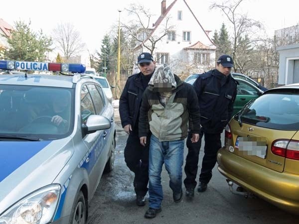 Policjanci doprowadzają do szczecineckiej prokuratury podejrzanych w kapturach naciągniętych na głowy. 