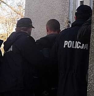 Policjanci prowadzą jednego z zatrzymanych