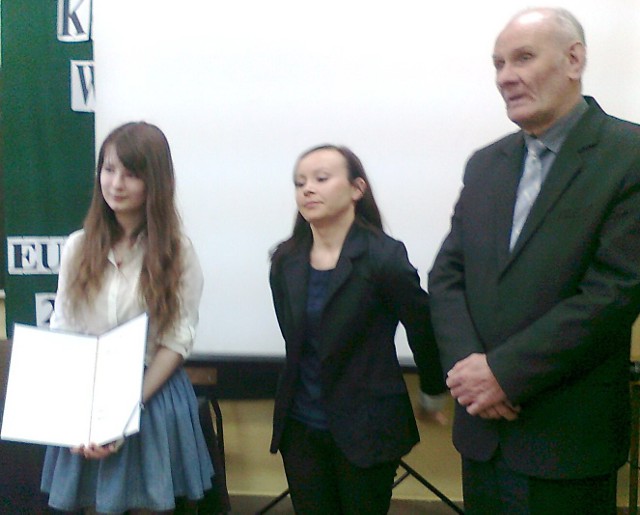 Karolina Bugajniak (z lewej) prezentuje wygrany bilet do Brukseli, wręczony przez przedstawicielkę Biura poselskiego europosła Czesława Siekierskiego w obecności sekretarza powiatu włoszczowskiego Romana Wojtalczyka.