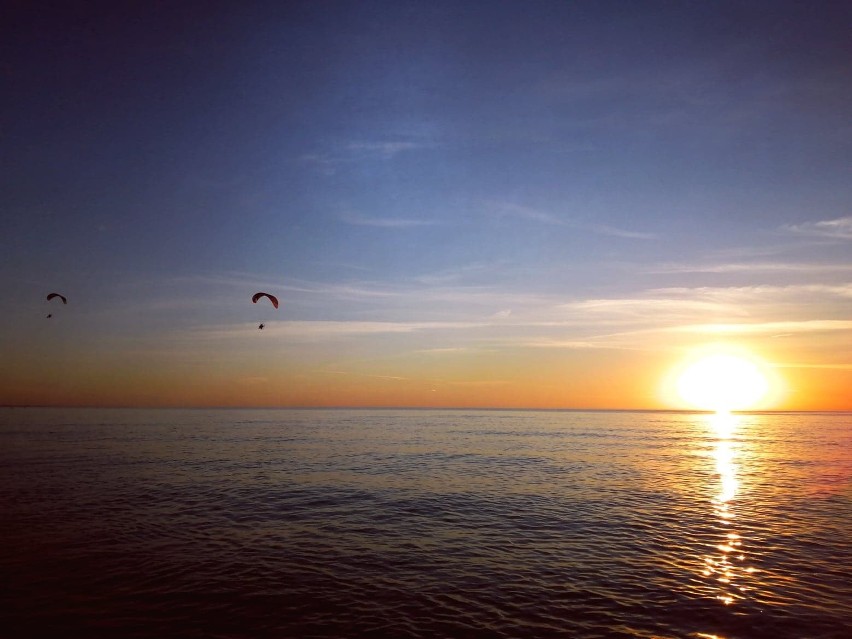 Motoparalotnie i deski SUP nad morzem na tle zachodzącego słońca [ZDJĘCIA]