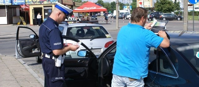 Policjant kontroluje jednego z taksówkarzy w pobliżu białostockiego dworca PKS