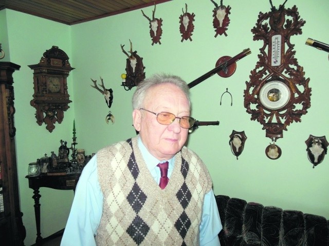 Z lewej strony Janusza Litwina wisi zegar z domu Bakeleya, z prawej - poroża i barometr
