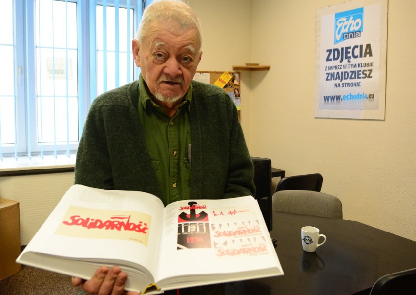 Krzysztof Mańczyński pokazuje swój plakat w albumie.