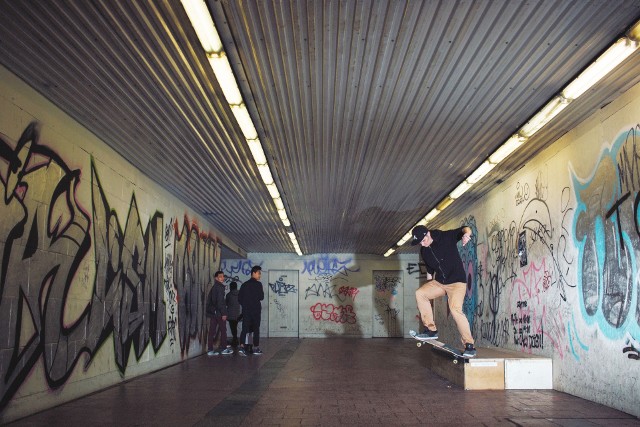 Przechodnie przyglądają się ewolucji deskorolkowej w przejściu podziemnym. Na zdjęciu: Adam Ulman, fakie ollie switch crooked grind.