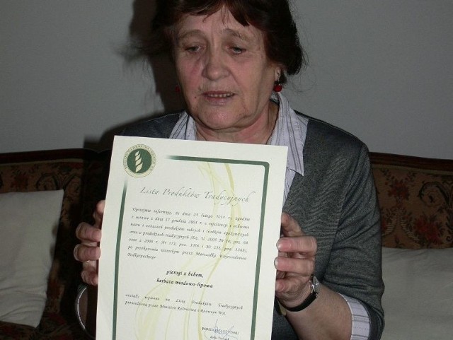 Maria Piwińska, wiceprezes stowarzyszenia z satysfakcją prezentuje certyfikat dokumentujący wpisanie na Listę Produktów Tradycyjnych Ministra Rolnictwa i Rozwoju Wsi herbaty miodowo-lipowej i pierogów z bobem,
