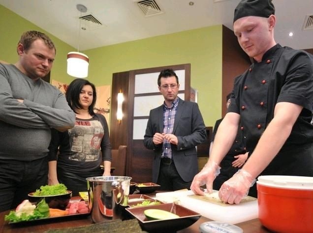 Sushi master Mateusz Najberg pokazuje uczestnikom warsztatów, jak przygotować sushi.