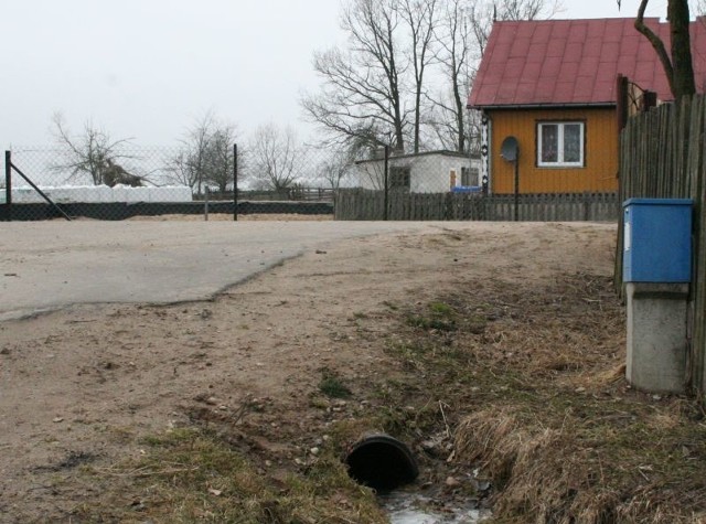 Woda wydostająca się z tej rury zalewa drogę i podwórka