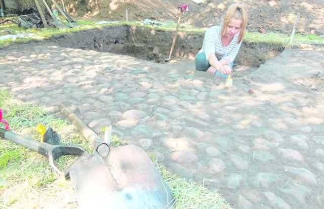 Agnieszka Lewandowska, absolwentka Instytutu  Archeologii UŁ, przeprowadza podczyszczanie kamiennego bruku, który przez lata był schowany pod ziemią